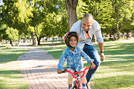 Father teaching child how to ride a bike family summer activities