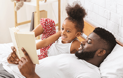 Father laying with daughter reading her a bedtime story how to connect with my kids